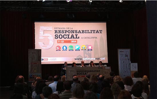 ponencia de la 5a semana de la responsabilidad social en Barcelona. 5 ponentes delante de una pantalla de proyección. público sentado escuchando. Catalunya
