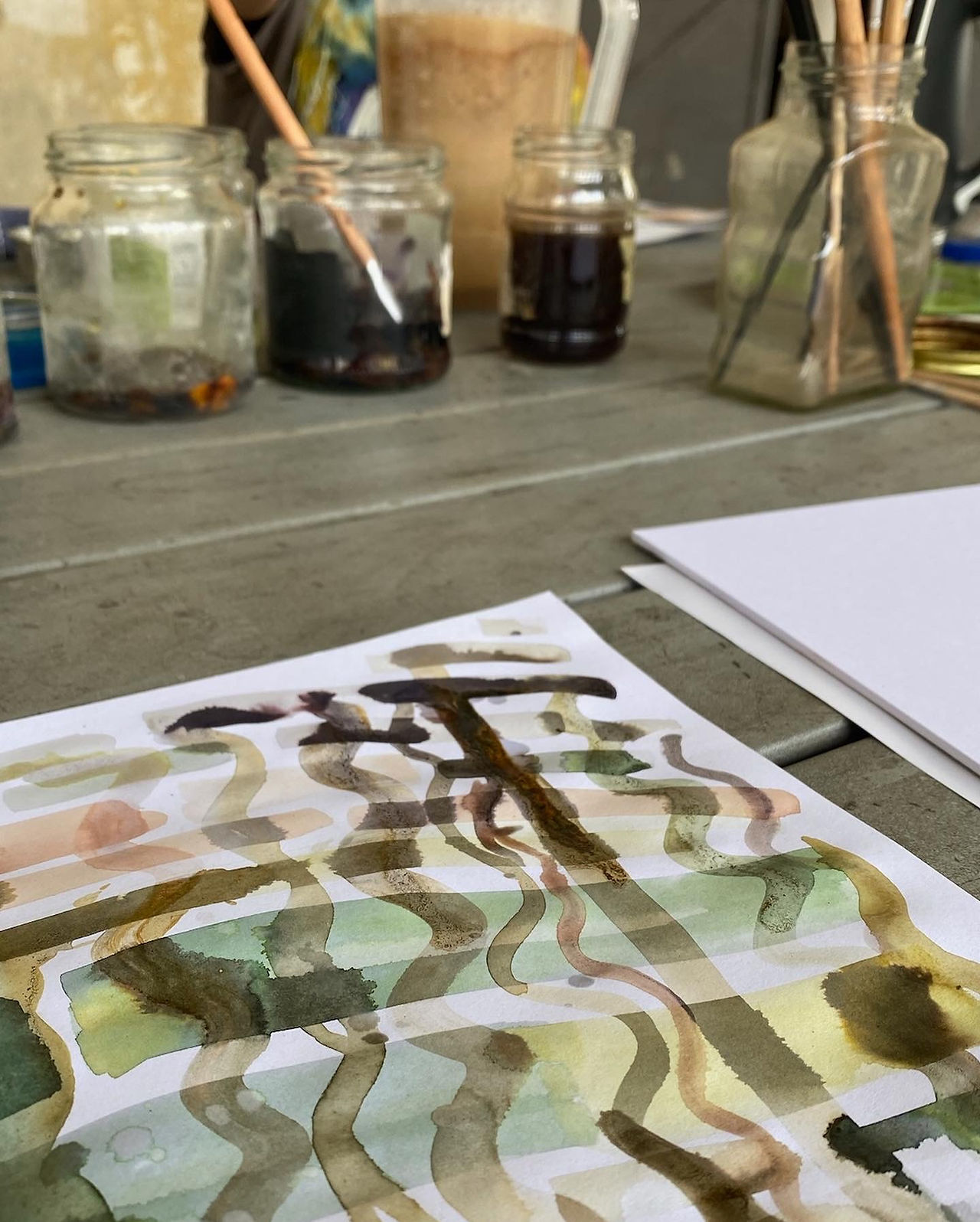 Drawing made with different natural ink colors with jars of plant inks in the background