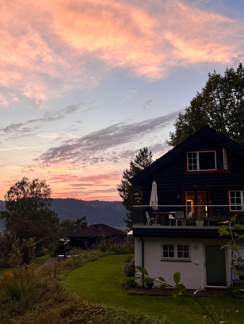 A sunset with purple-pink skies and with a cottage view