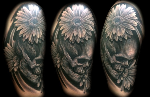 black and grey skull with daisies tattoo by Joe Riley