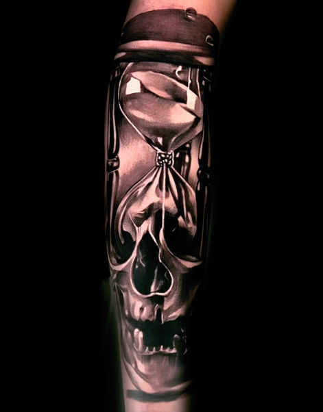 black and grey tattoo of a skull and hourglass