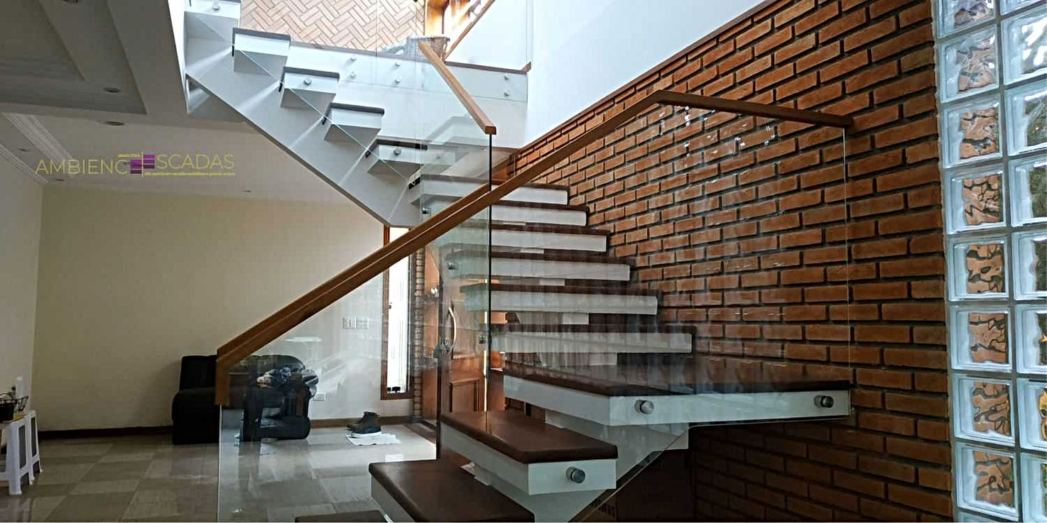 Guarda corpo em vidro fixado em lateral de escada e mezanino por botões de aço inox maciços. Corrimão de madeira encaixado diratamente em vidro de guarda corpo. Guarda corpo instalado em residência em Guarulhos.
