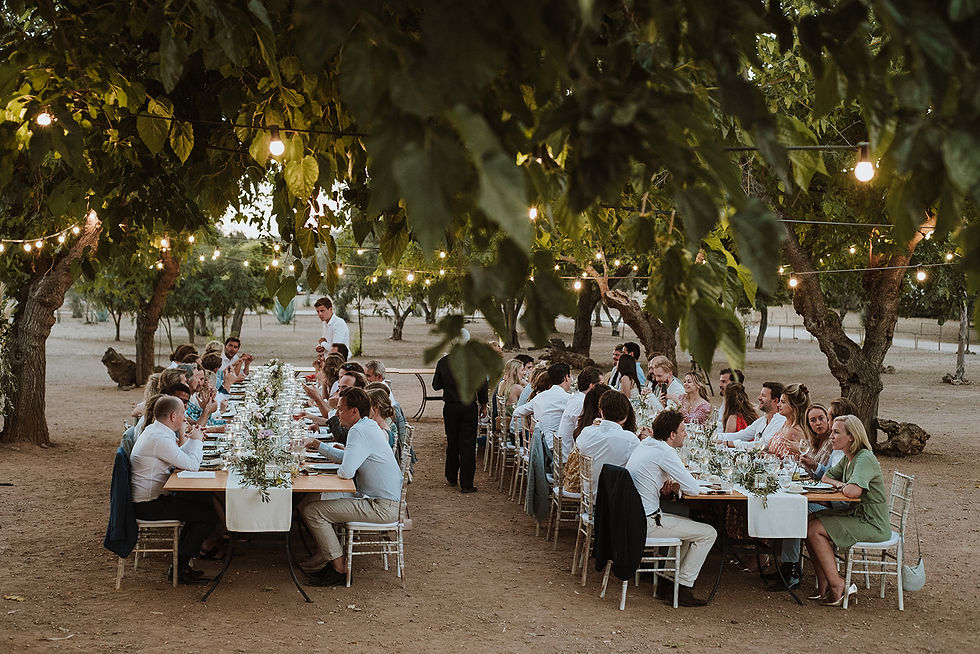 Al fresco wedding dinner at two long tables with fairy lights