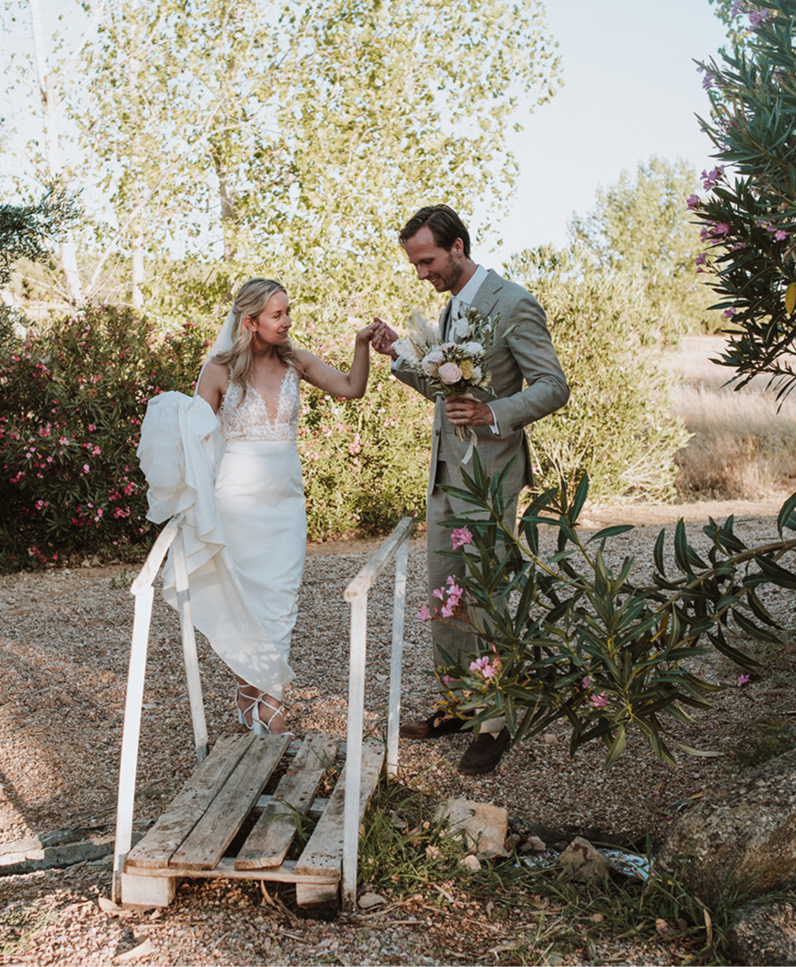 Bride walks over a bridge while groom holds her hand