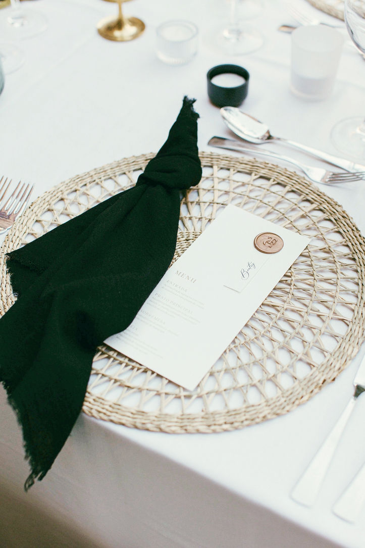 Wicker woven charger plate with black napkin and white menu with wax seal