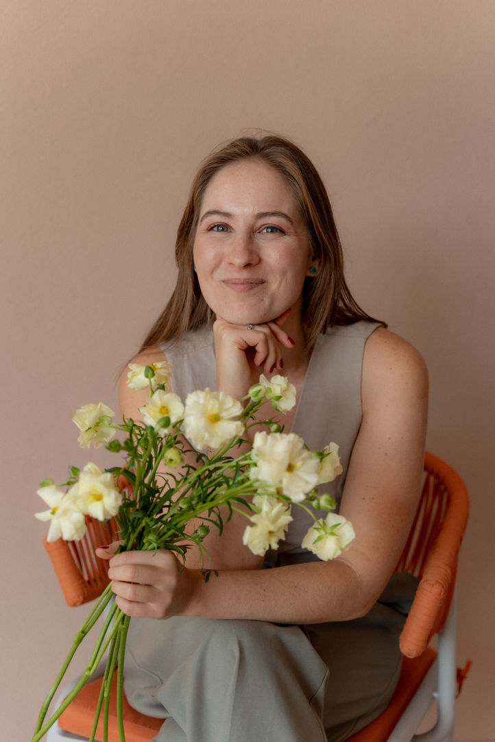 Girl seated on a chair with bunch of flowers in her hand