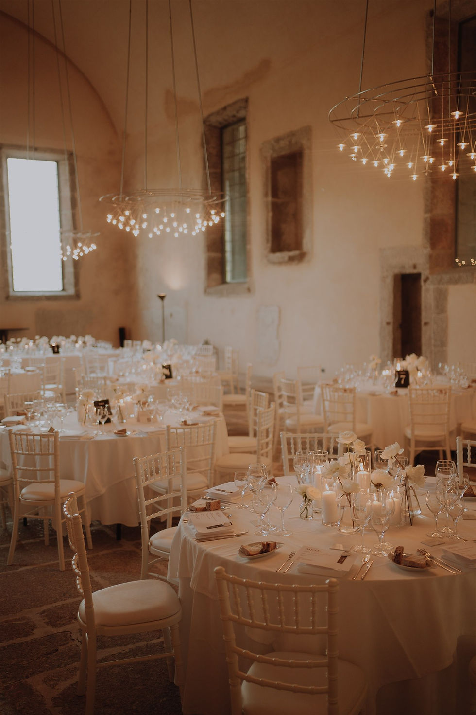 Dining room with high curved ceilings and modern chandeliers, decorated for a wedding dinner