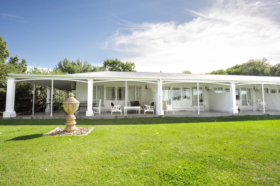 Exterior view of La Riviera Guesthouse with white veranda.