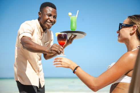 Resort staff serving drinks to guest at tropical beach resort