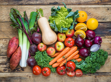 Assorted fresh vegetables and tropical produce arranged on wooden table