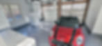 A garage with concrete floor and a red car