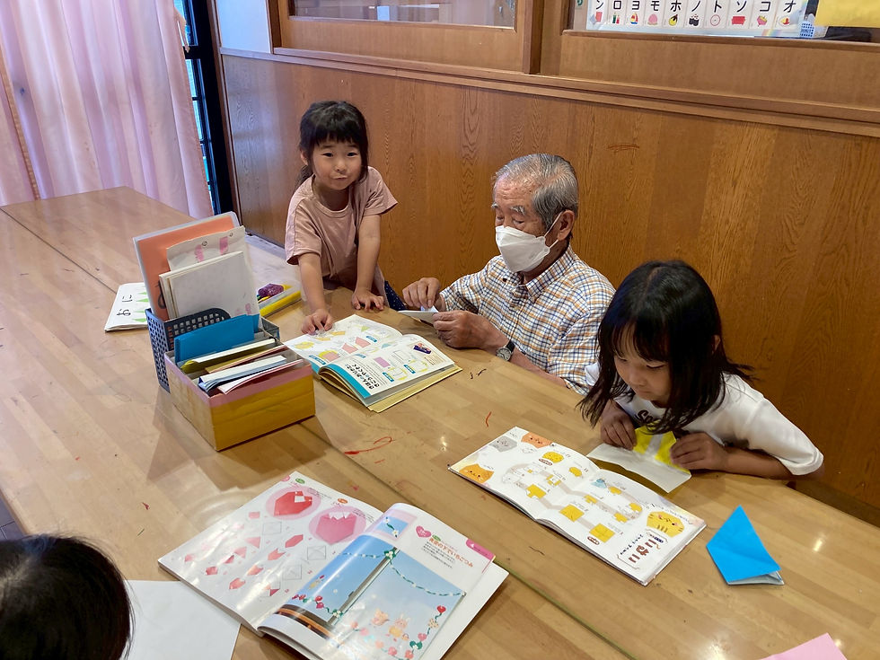 折り紙の折り方を教えてもらう4歳児