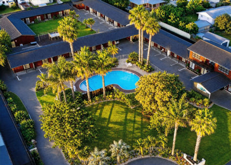 Aerial view of a Gisborne motel with a swimming pool and palm trees