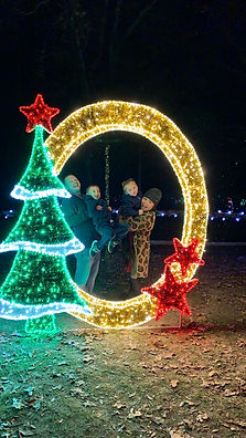 A family of four posing within the light Christmas photo op, surrounded by a golden circle with red stars and a Christmas trees.