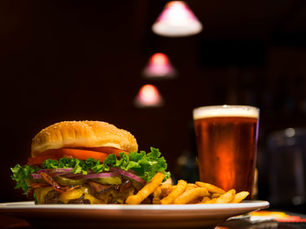 A hamburger and fries on a plate next to a glass of beer