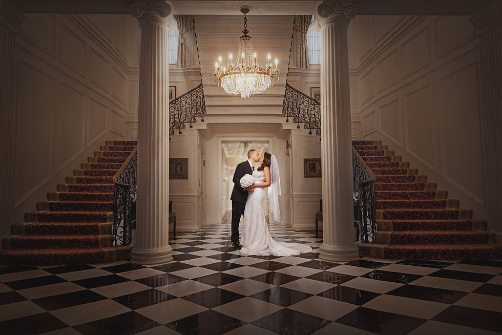 A bride and groom in the hallway of the glen cove mansion sharing a warm embrace Photo Captured by Wedding Photographer George Pompilio