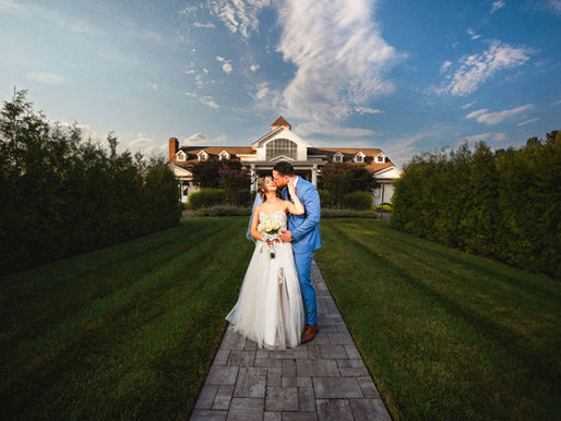 A couple dances romantically on a stone ledge in a garden with lush greenery and flower urns. The setting sun adds a warm glow.