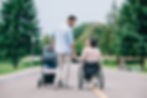 Couple walking down a road with stroller and woman in wheelchair