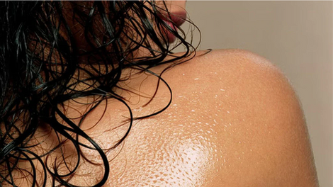 Spalla e capelli bagnati con pelle idratata dall’olio naturale Intensive DermaCalm – trattamento per pelle, cuoio capelluto e barba disponibile da Ardor Nail & Spa Studio.