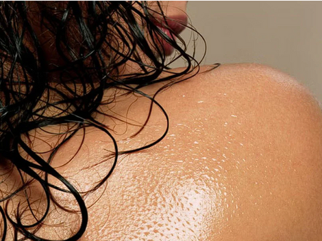 Spalla e capelli bagnati con pelle idratata dall’olio naturale Intensive DermaCalm – trattamento per pelle, cuoio capelluto e barba disponibile da Ardor Nail & Spa Studio.