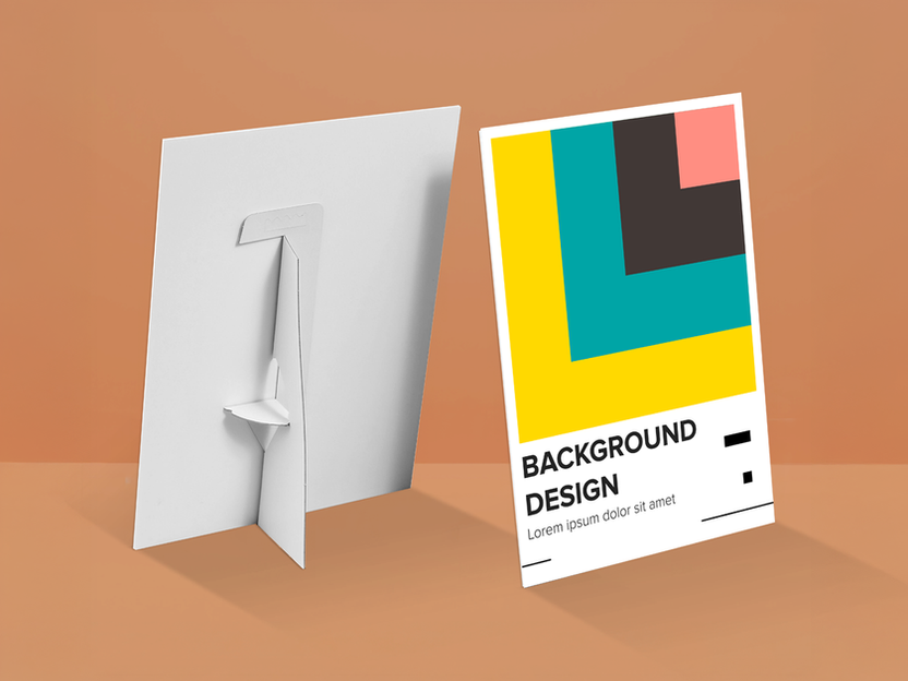 A printed card with a geometric design in yellow, teal, pink, and black, alongside the text "BACKGROUND DESIGN" and filler text, next to a blank white card with a cardboard stand attached to the back.