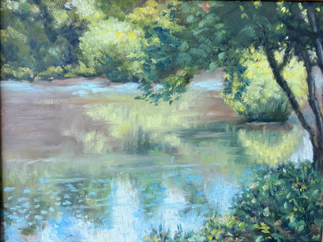 Peaceful river scene, sunlit trees reflected in calm water