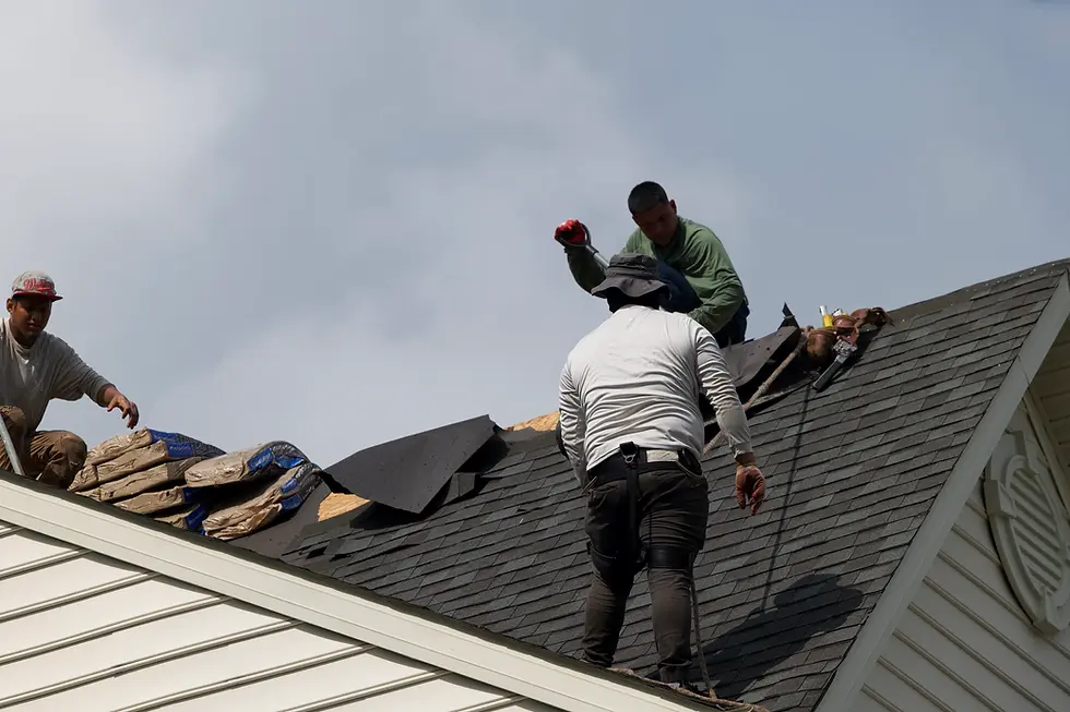 three-roofers-working-on-steep-asphalt-shingle-roof-installation-with-tools-and-materials-under-cloudy-sky