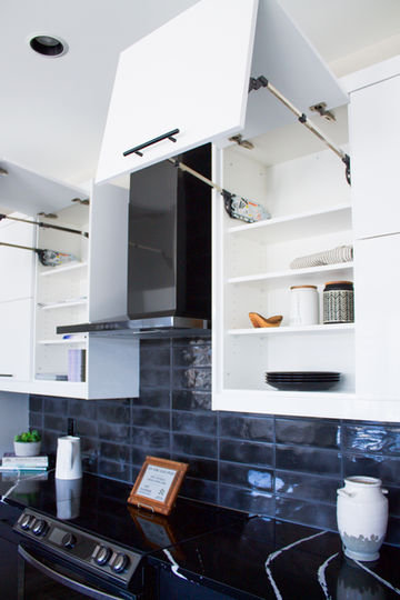 Modern white cabinets are opened to reveal an organized interior in a stunning, contemporary kitchen design from Imperial Cabinet in Winnipeg, Manitoba.