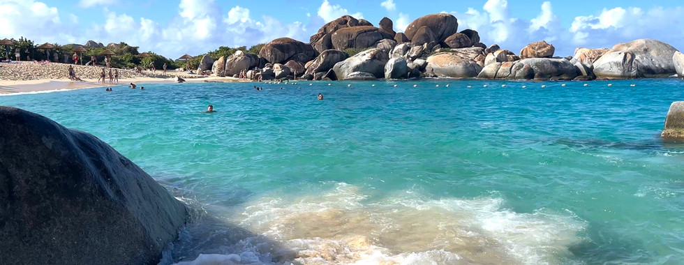 Virgin Gorda exotic beach with huge boulders and turquoise water and people swimming