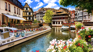a picturesque canal in la Petite France with timbered houses, flowers and boats