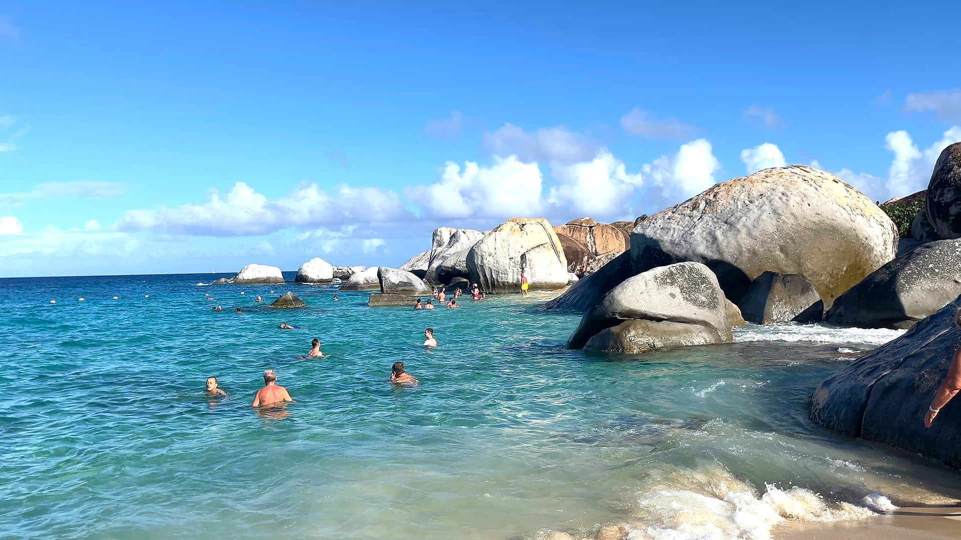 Virgin Gorda beach with huge boulders and turquoise water and people swimming