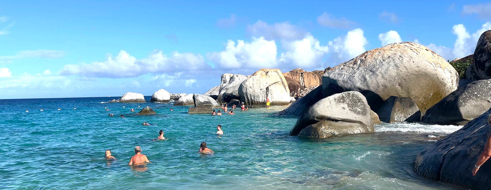 Virgin Gorda beach with huge boulders and turquoise water and people swimming