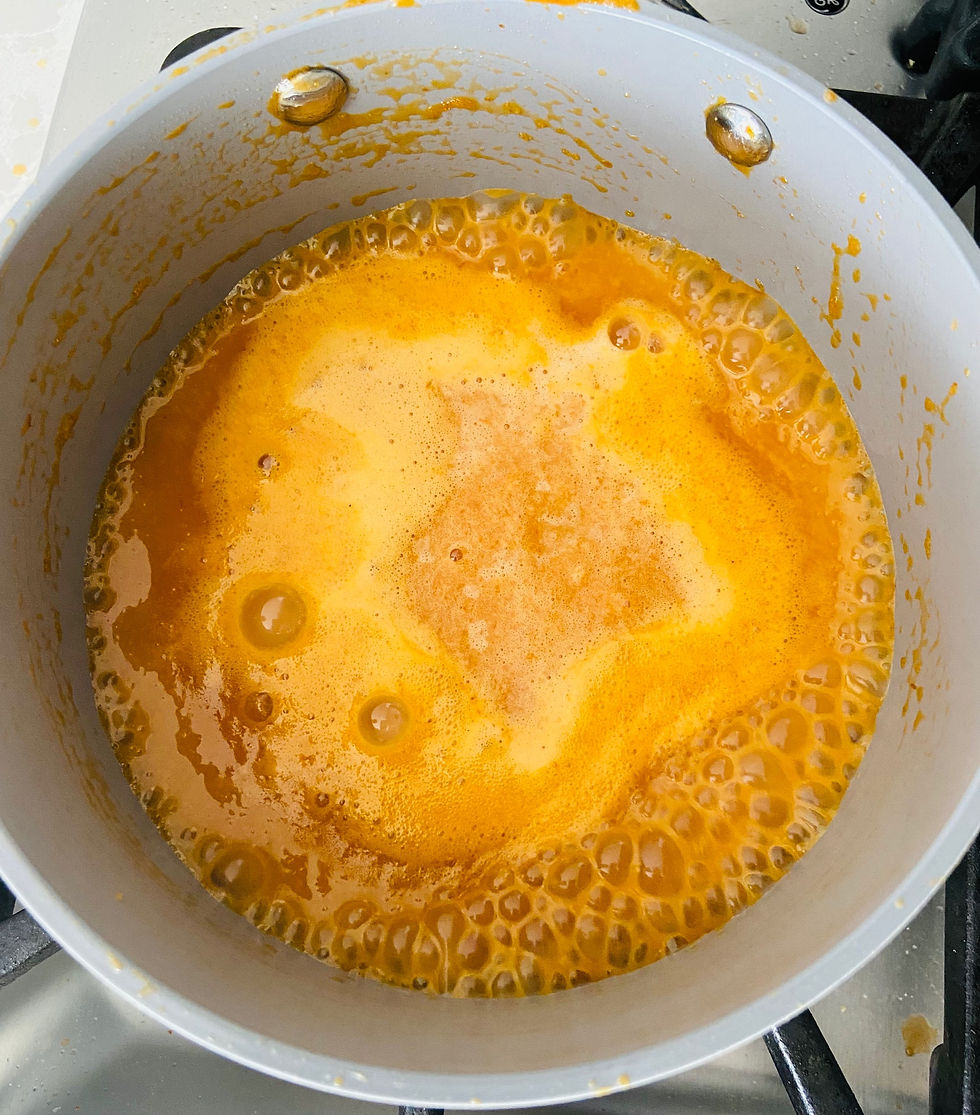 Orange wing sauce in a grey sauce pot simmering