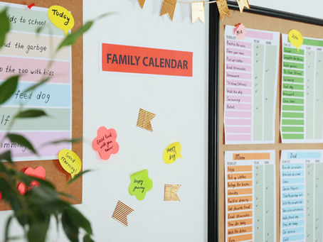 A family calendar on a wall with individual charts for each family member.