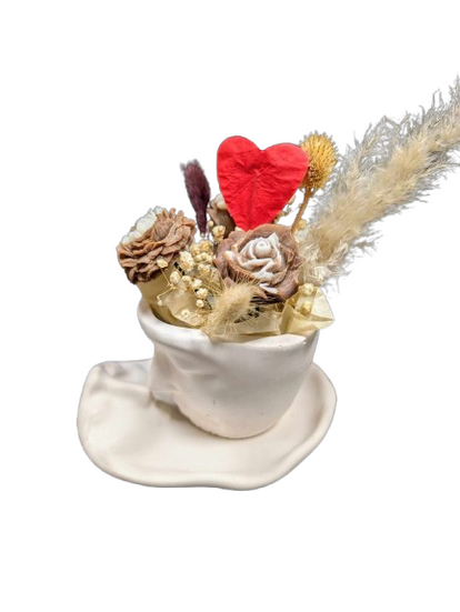 Composition parfumée Saint-Valentin dans une tasse en céramique blanche avec des fleurs décoratives, un cœur rouge et des éléments naturels.