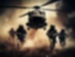 Soldiers running towards the camera with a helicopter overhead in a warzone