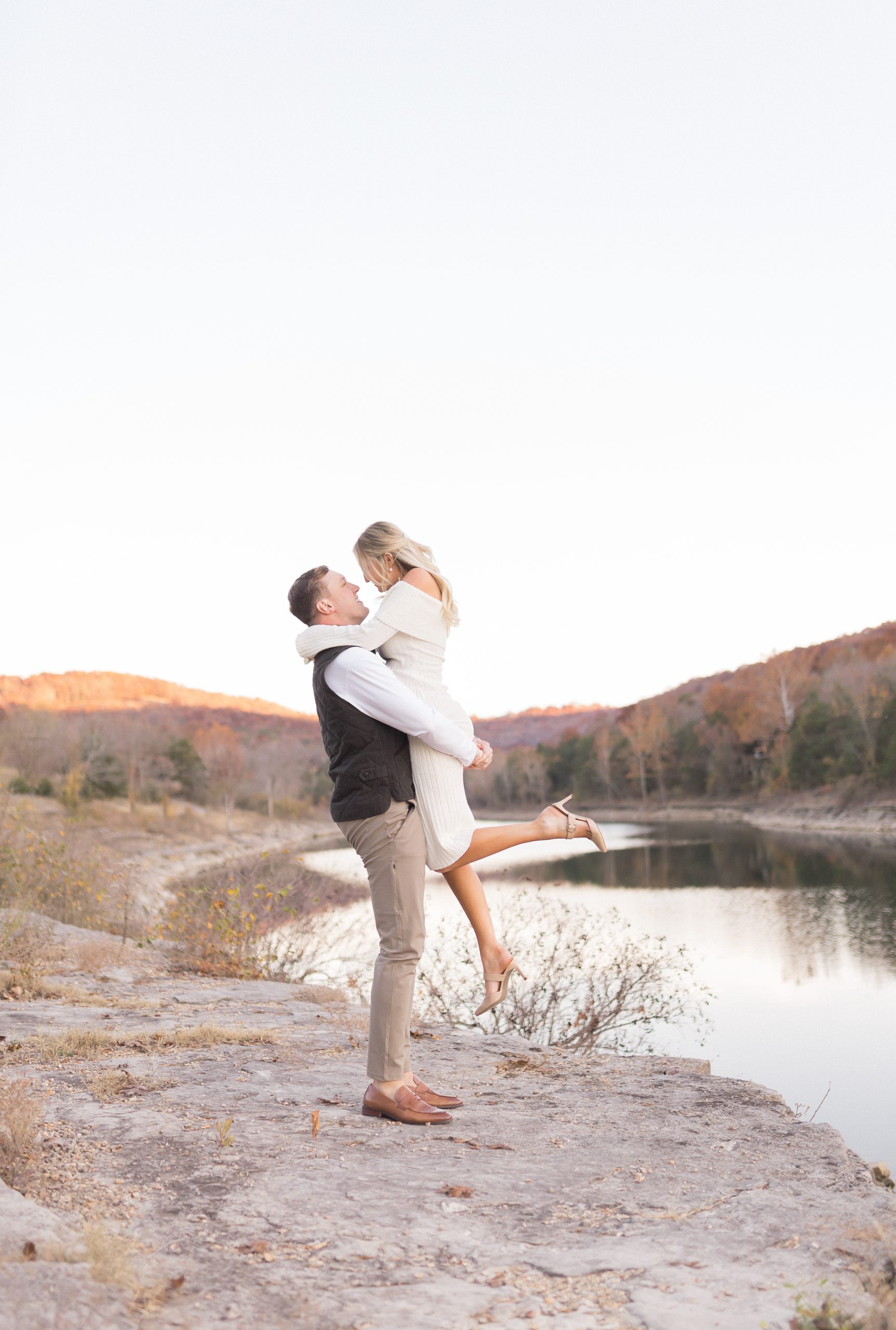 Couple kissing lakeside at sunset.