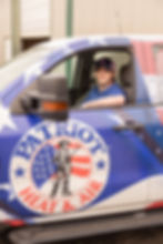 Patriot Heat & Air technician sitting in a branded service vehicle with the company logo visible on the door.