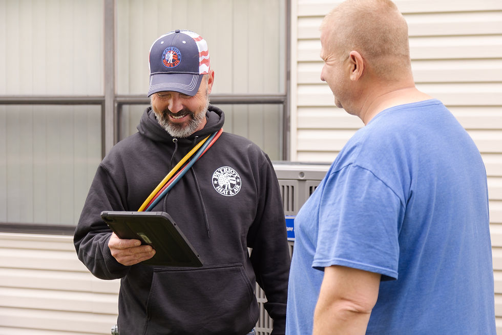 Patriot Heat & Air technician reviewing service details with a homeowner outside their home.