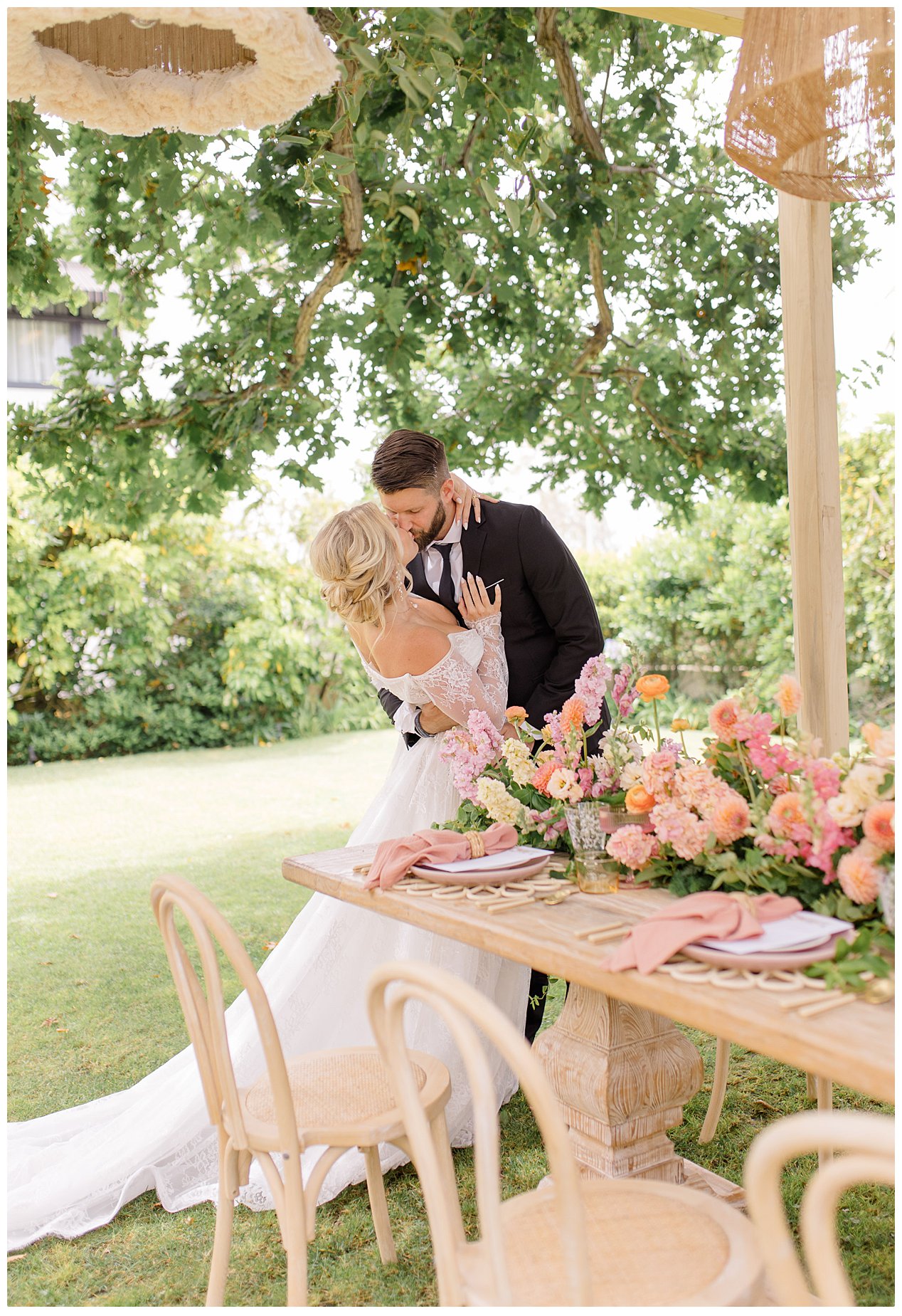 Bride and Groom kissing by a beautiful tablescape at an outdoor wedding venue.