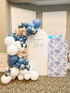 Elegant Bonjour Bébé baby shower balloon installation featuring blue, ivory and white balloons, floral accents and custom arch backdrops.