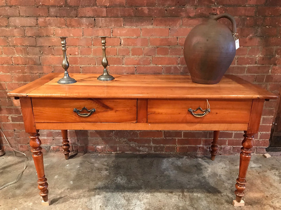 Antique wooden serving table with two drawers, candlesticks, and a large jug