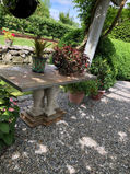 Stone table outdoors with plants in pots, garden setting. Antique furniture modern classic.