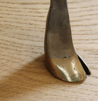 Close up of a unique bronze deer foot base, on wooden flooring.