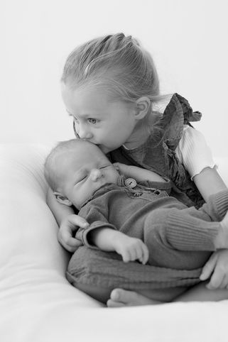 Süße ältere Schwester küsst schlafendes Neugeborenes