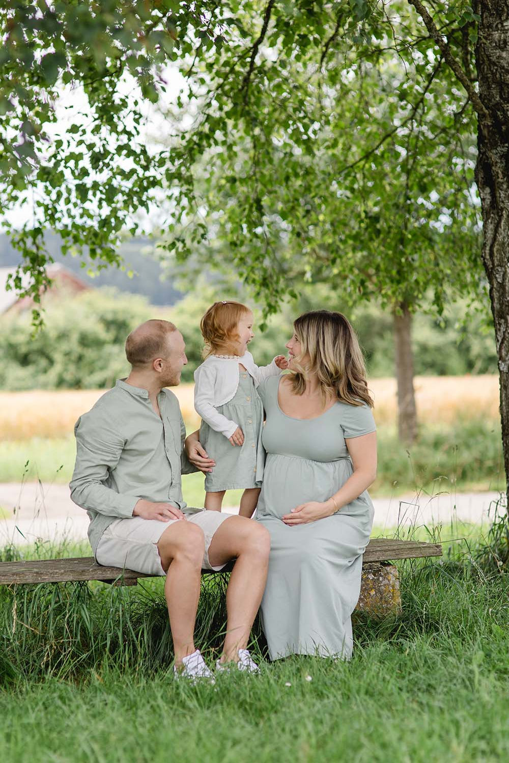 Familie im Grünen: Schwangere Frau, Mann und Kind
