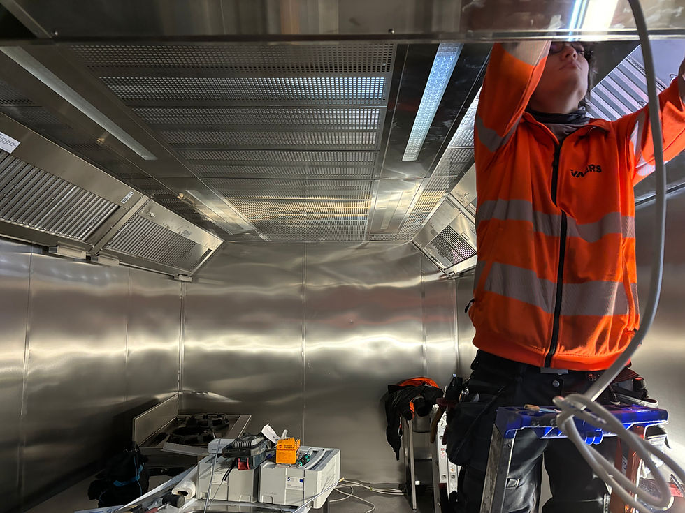 An IVAeris technician opens a restaurant kitchen canopy structure and access hatch to begin brushing and cleaning the grease duct. The image relates to the Grease Duct Cleaning service (statutory annual cleaning, fire safety, and performance verification).