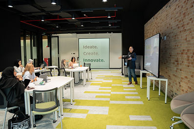 A mentor gives a presentation to a group of people in Innovate for Bahrain space.