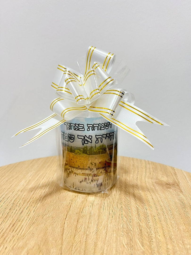 תמונה ממוזערת: כוס לנר נשמה with white ribbons and text. Wrapped on a wooden base.