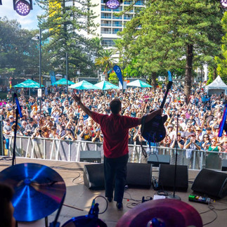 Performer on stage with arms raised at Blues on Broadbeach 2025 — accommodation nearby at Burleigh Gold Coast Motel